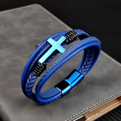Blue braided leather bracelet with a cross charm on a gray surface